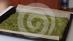 A woman puts on a table a baking sheet with baked cake. The process of making Swiss roll