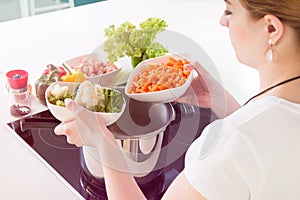Woman puts vegetables into the pressure cooker.