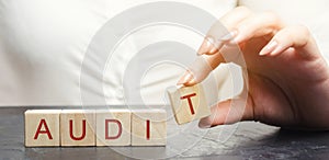 A woman puts wooden blocks with the word Audit. Inspection of financial and economic activities of institutions and enterprises.