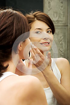 Woman putting anti-aging cream on her face.