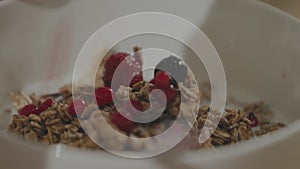 Woman putting berries on a cereal oatmeal breakfast