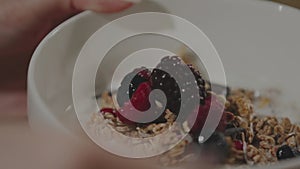 Woman putting berries on a cereal oatmeal breakfast