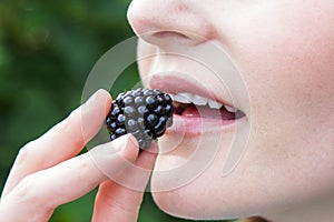 Woman putting blackberry into mouth