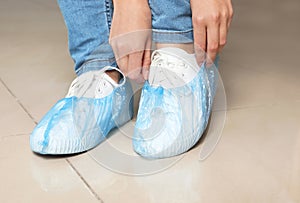 Woman putting on blue shoe covers