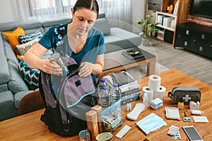 Woman putting cans of food to prepare emergency backpack