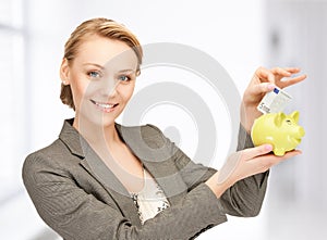 Woman putting cash money into small piggy bank