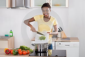 Woman Putting Chopped Vegetables In Utensil