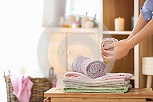 Woman putting clean soft towels on table in room