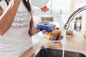 Woman putting cleanser to a sponge. Hand washing dishes