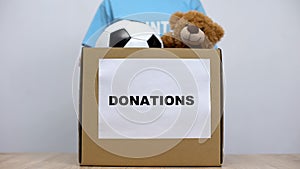 Woman putting clothes and toys in donation box, social volunteering project