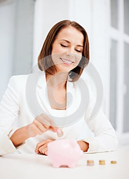 Woman putting coin into piggy bank