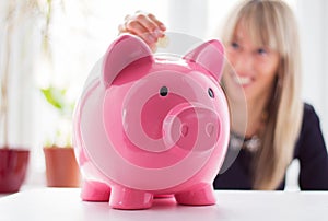 Una mujer introducción monedas en pequeno cerdo Banco 