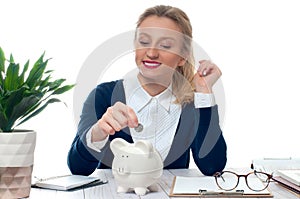 Woman putting coin in piggy bank. Saving concept