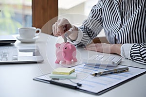 Woman putting coin into piggy bank. Saving money, banking, economy concept.