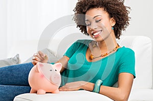 Woman Putting Coin In Piggybank