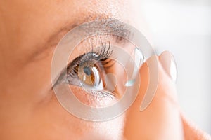 Woman putting contact lens for better vision.