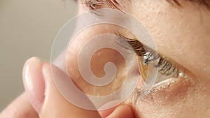 woman putting on contact lens close-up, Brown eyes