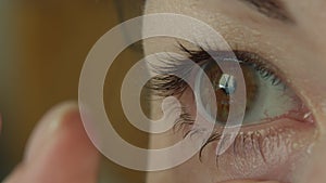 Woman putting contact lens on her eye