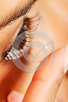 Woman putting contact lens in her eye