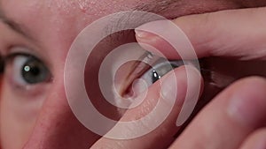 Woman putting contact lens in her eye. Close up