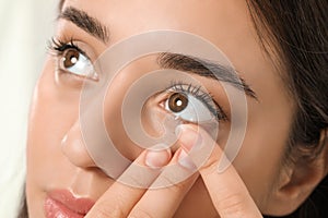 Woman putting contact lens in her eye, closeup view