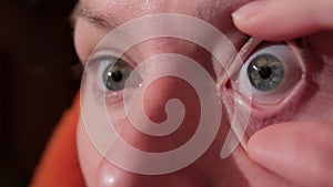 Woman putting contact lens in her eye and loses it.