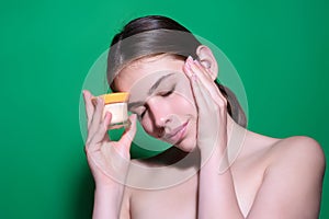 Woman putting cosmetic cream. Spa model applying skincare product on her face. Morning make-up. Moisturizing skincare