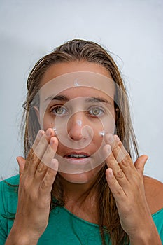 Woman putting cream on her face to hydrate it