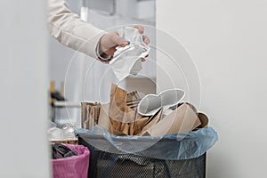 Woman putting crumpled paper into trash bin