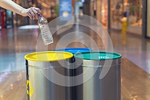 Woman putting empty plastic bottle in recycling bin in the mall