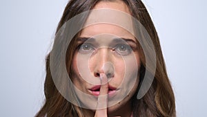 Woman putting finger on mouth in studio. Attractive woman showing silence sign