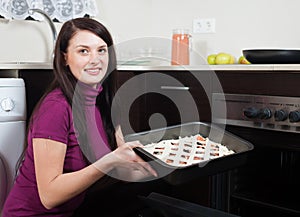 Woman putting fish pie on roasting pan into oven