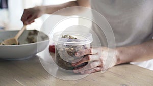 Woman putting fish salad and bean into plastic box slow motion