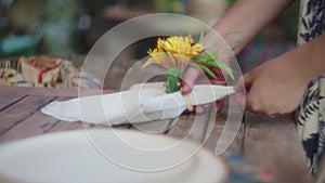 Woman putting a flower arrangement onto the napkin, preparing the dining table