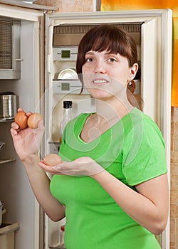 Woman putting fresh eggs into refrigerator