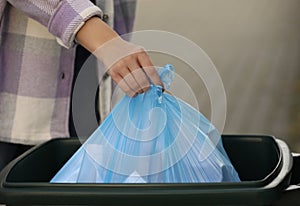 Woman putting garbage bag into recycling bin outdoors, closeup