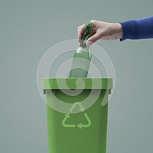 Woman putting a glass bottle in the trash bin