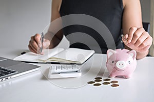 Woman putting golden coin in pink piggy bank for step up growing business to profit and saving with piggy bank, Saving money for