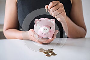 Woman putting golden coin in pink piggy bank for step up growing business to profit and saving with piggy bank, Saving money for