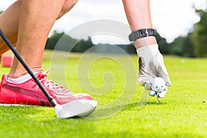 Woman putting golf ball on tee, close shot