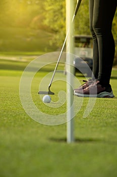 Woman Putting on the Green with Golden Sun Light