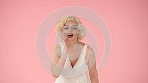Woman putting her hand to her mouth that screams, calling someone. Woman in the look of Marilyn Monroe in the studio on