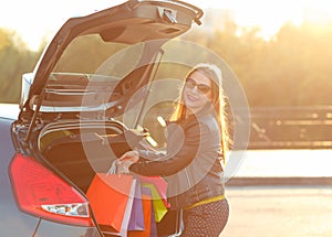 Woman putting her shopping bags into the car trunk