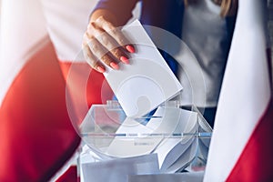 Woman putting her vote to ballot box. Poland political elections