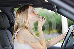 woman putting on lipstick in car