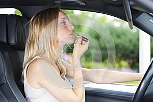 Woman putting on lipstick in car