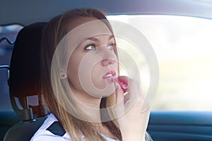 Woman putting make up in a car. Pretty young woman looking in mirror. Dangerous situation.