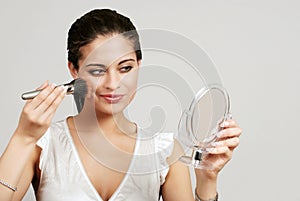 Woman putting on makeup with blush brush