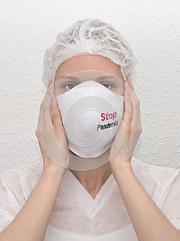 A woman putting on a medical mask with sign Stop Pandemia to avoid contagious viruses.