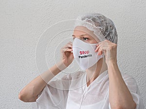 A woman putting on a medical mask with sign Stop Pandemia to avoid contagious viruses photo